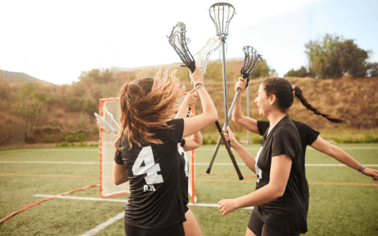 A group of women playing lacrosse on a grassy field, passing the ball and maneuvering around each other with determination and focus