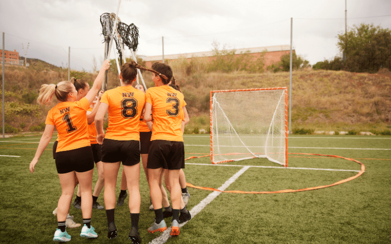 Women playing lacrosse, showing strength and skill. Injuries are evident, but they persevere